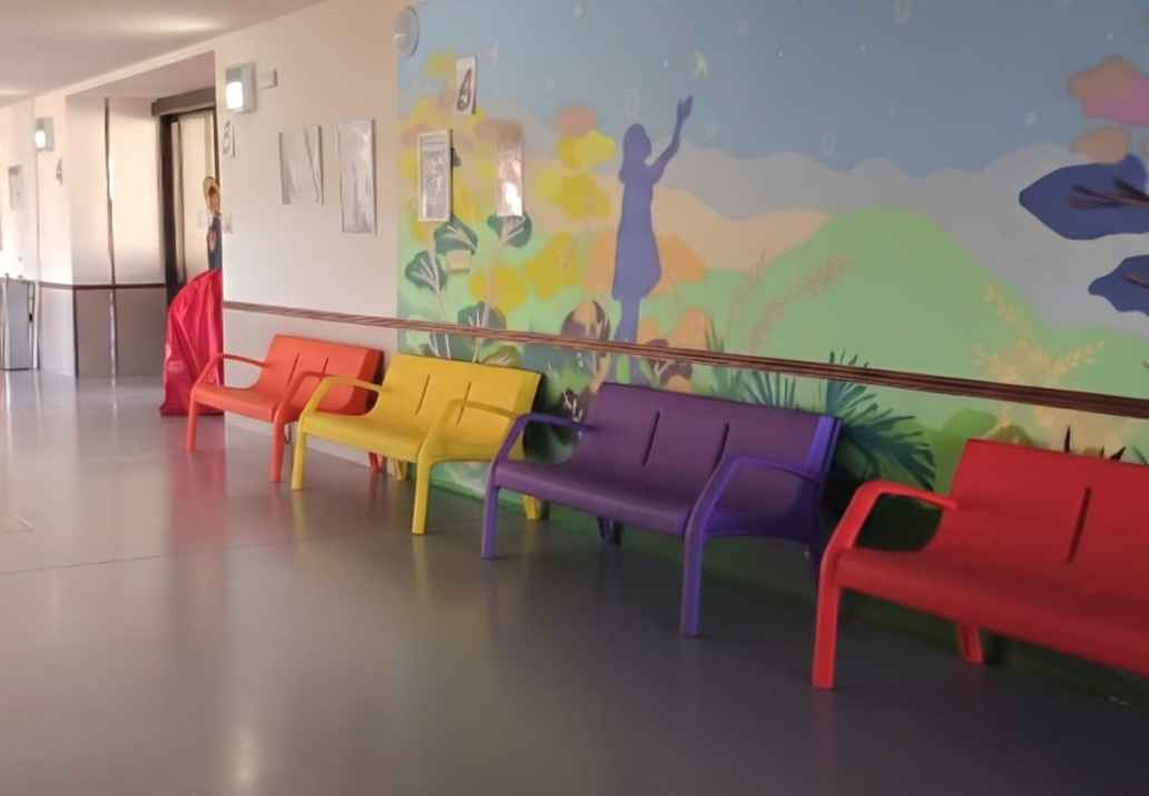 se ven un pasillo con murales y bancos de colores